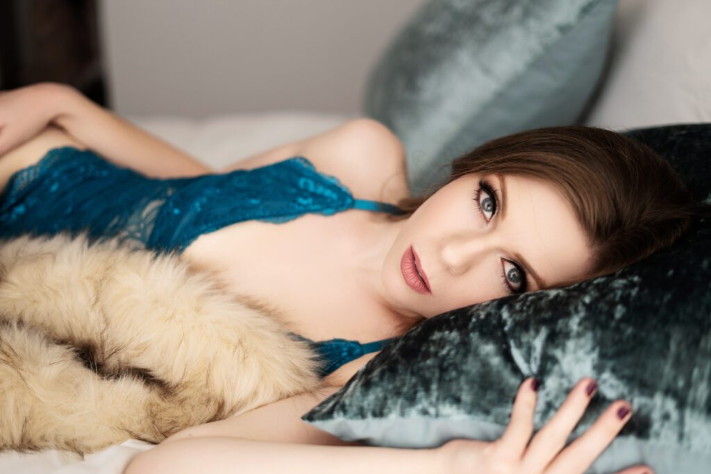 woman laying on ben in teal lingerie with fur blanket